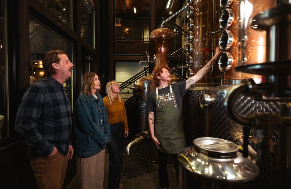 Three people take part in the PARK Distillery on-site tour with a guide in Banff National Park.